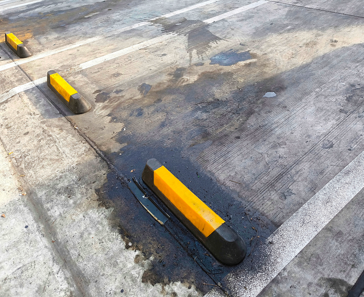 Oil-stained parking area with yellow barriers