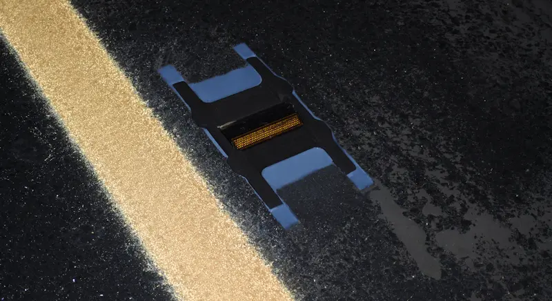 Road sensor on asphalt beside yellow line
